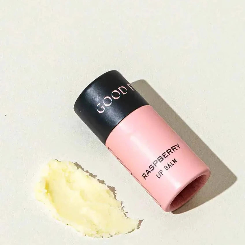 Pink lip balm with black cap on a light beige background
