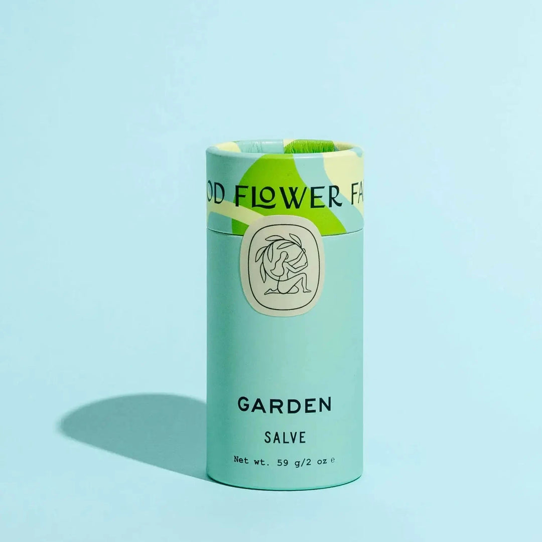 Green cylindrical container labeled 'Garden Salve' on a light blue background