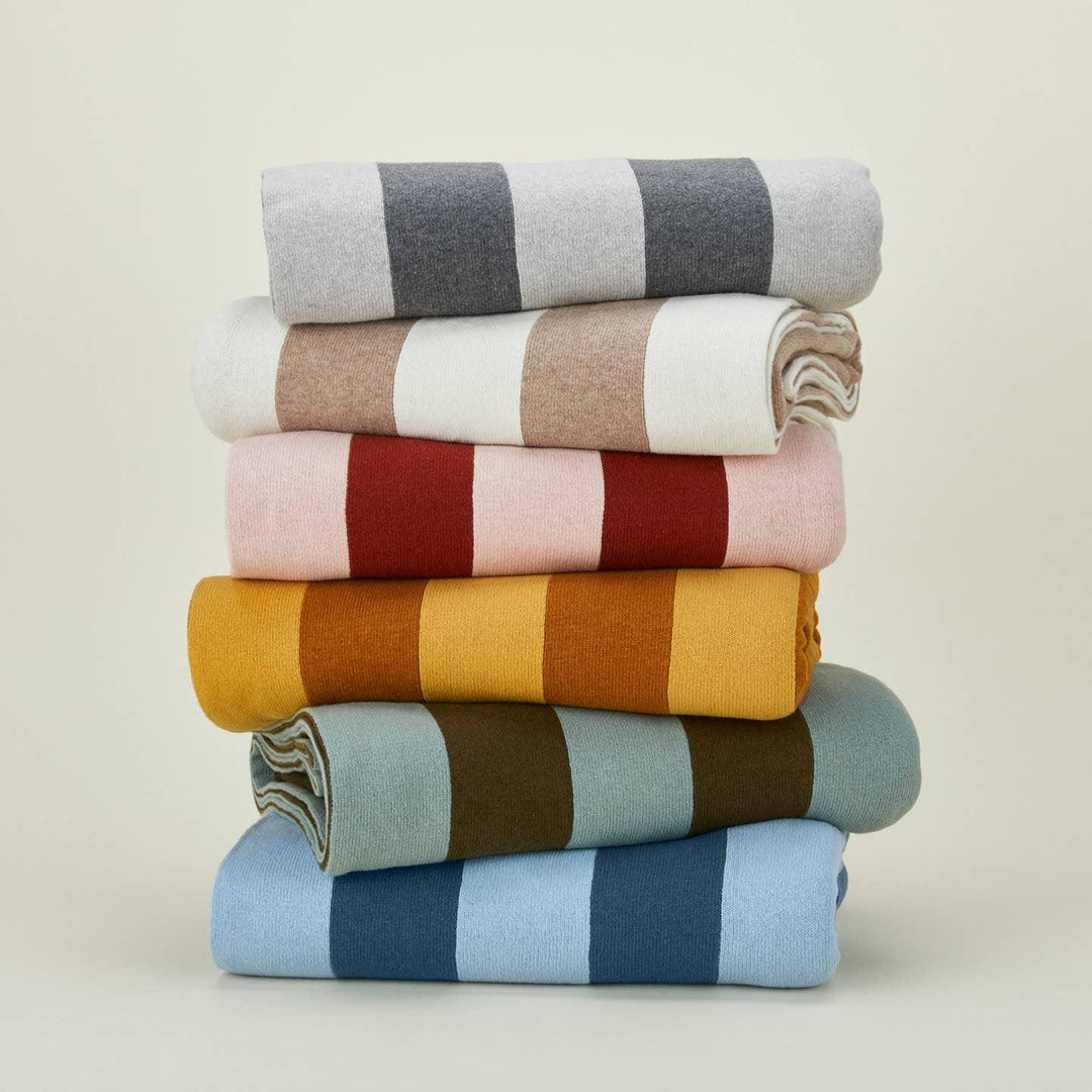 Stack of colorful striped blankets on a beige background