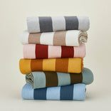 Stack of colorful striped blankets on a beige background