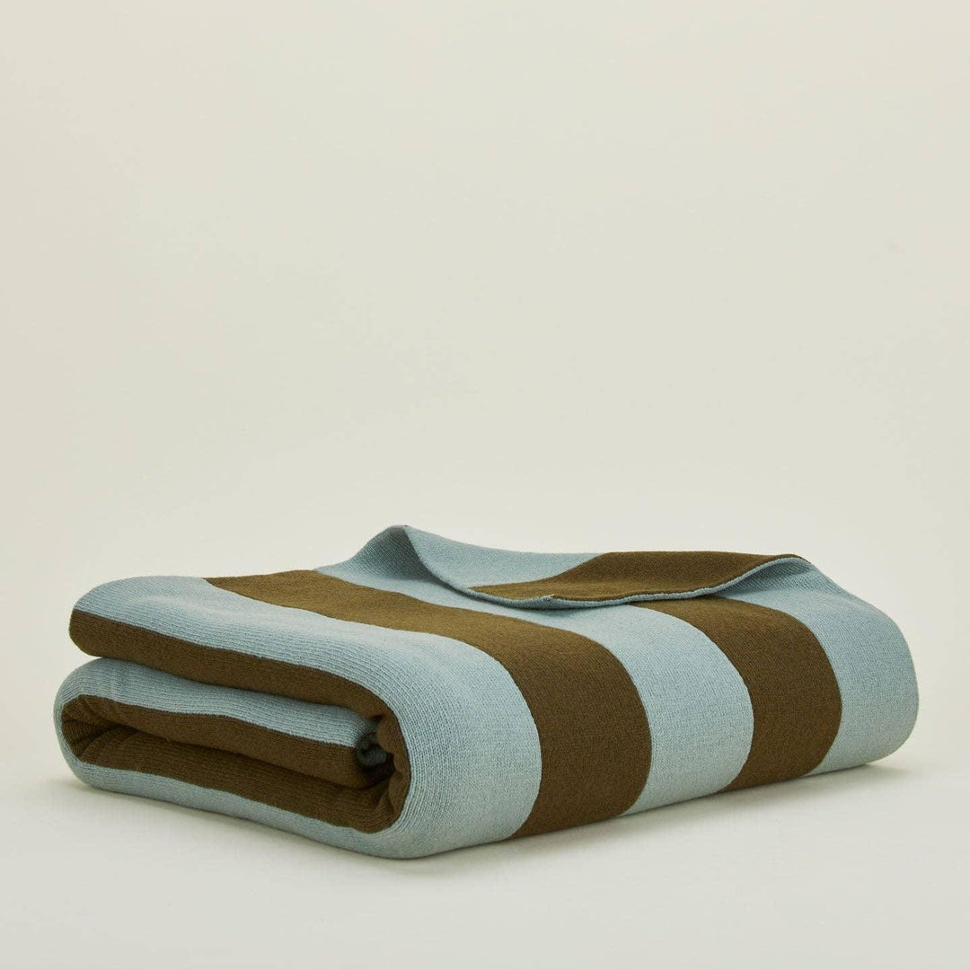 Folded blanket with brown and light blue stripes on a beige background