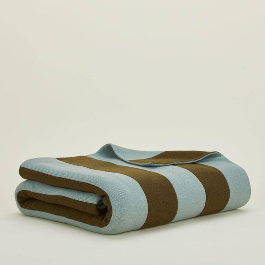 Folded blanket with brown and light blue stripes on a beige background