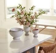 Elegant floral arrangement with soft pink blooms in a white vase on a marble countertop