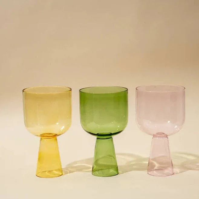 Three colorful glass goblets on a beige background