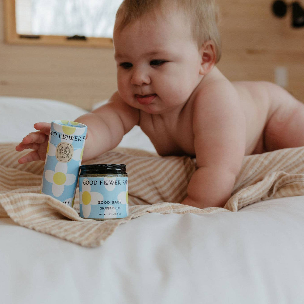 Baby playing with Good Flower Baby products on a bed
