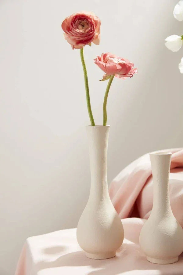 Pink ranunculus flowers in white ceramic vases, soft pastel setting