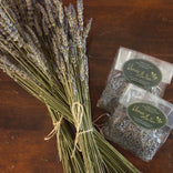 Dried lavender bundle on wooden table with two small bags of lavender buds.