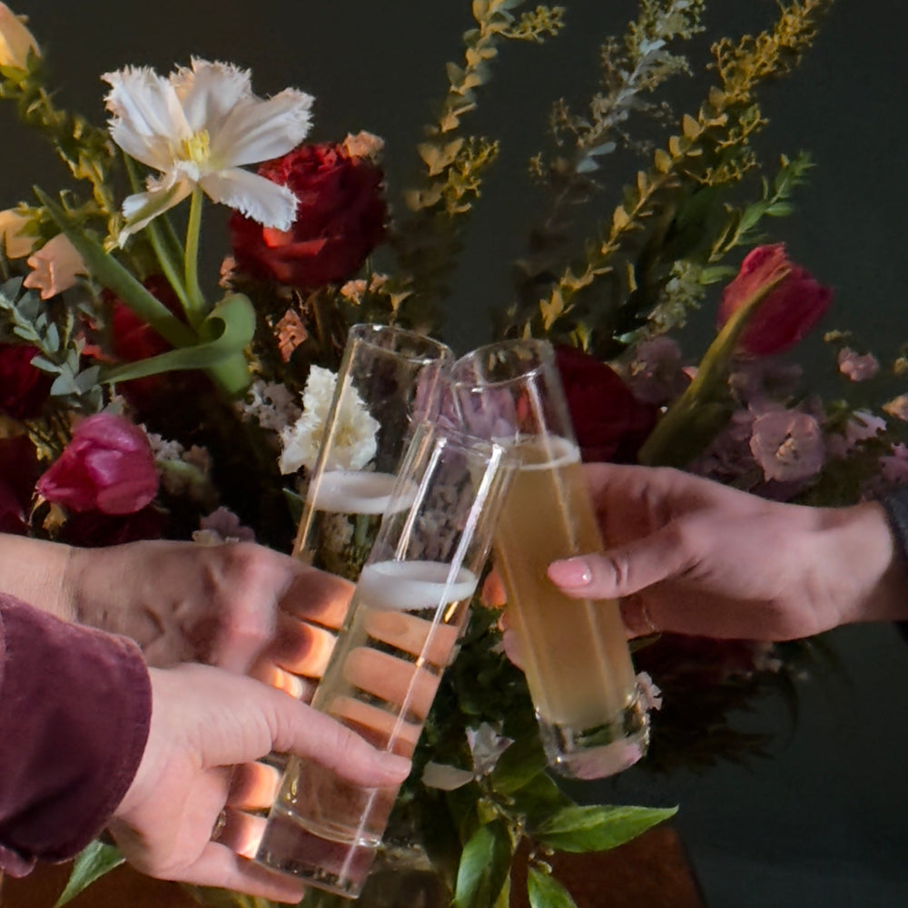 Three glasses of wine in front of a red and white tulip arrangement.